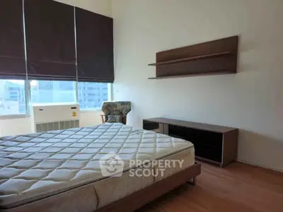 Spacious bedroom with large windows and modern furniture in a high-rise apartment.