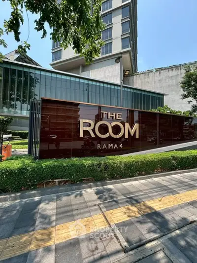 Modern condominium building exterior with sleek signage at The Room Rama 4, showcasing urban living in Bangkok.