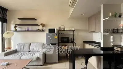 Modern open-layout living room with kitchen, featuring sleek furniture and appliances.