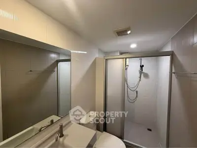 Modern bathroom with sleek shower and large mirror in contemporary apartment.