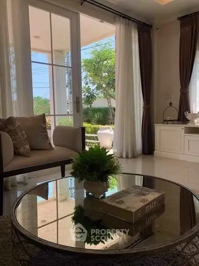 Elegant living room with glass coffee table and garden view, perfect for relaxation and entertaining.