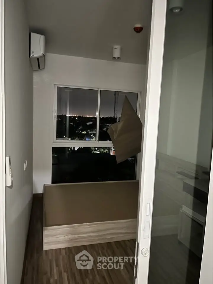 Cozy bedroom with city view, featuring modern flooring and air conditioning, perfect for urban living.