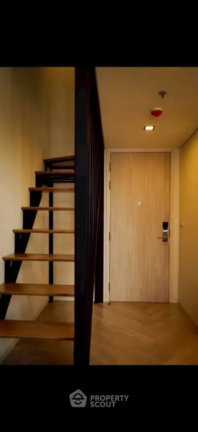 Modern apartment entrance with wooden staircase and sleek door design