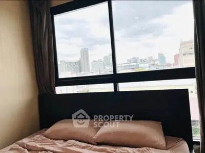 Cozy bedroom with city view through large window, perfect for urban living.