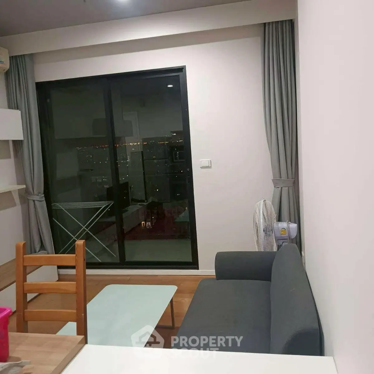 Cozy living room with modern furniture and city view balcony access.