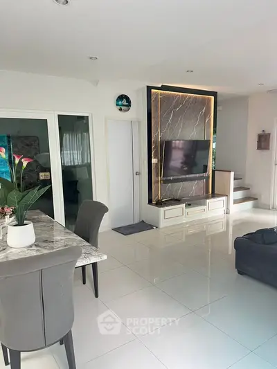 Modern living room with sleek marble dining table and stylish TV feature wall