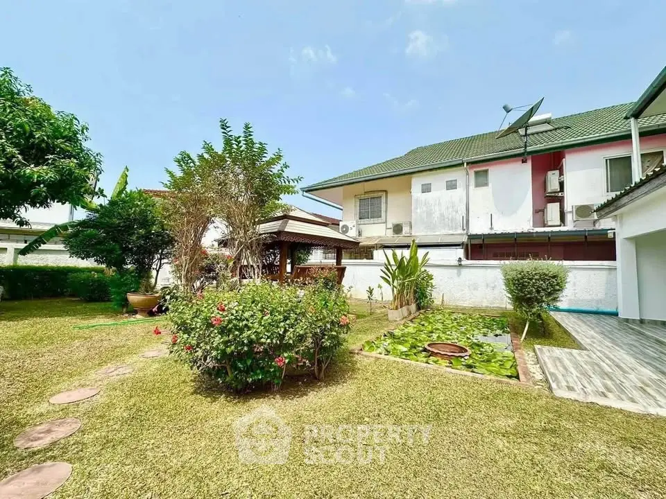 Charming garden view of a suburban home with lush greenery and a cozy gazebo.