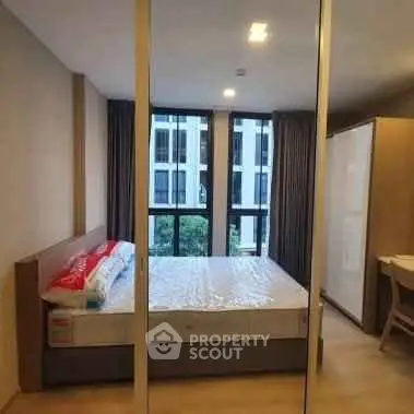 Modern bedroom with large windows and stylish furnishings in urban apartment.