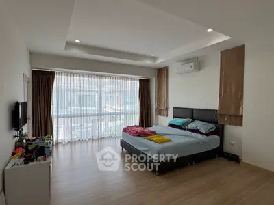 Spacious bedroom with modern decor and large windows for natural light