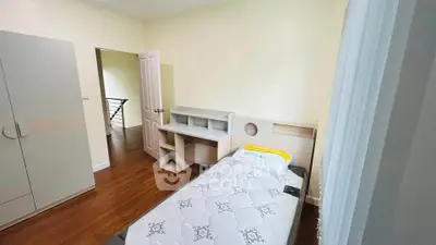 Cozy bedroom with single bed and wooden flooring, featuring a modern wardrobe and study desk.