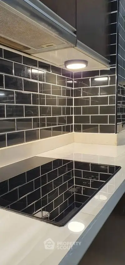 Modern kitchen with sleek black subway tiles and built-in electric cooktop