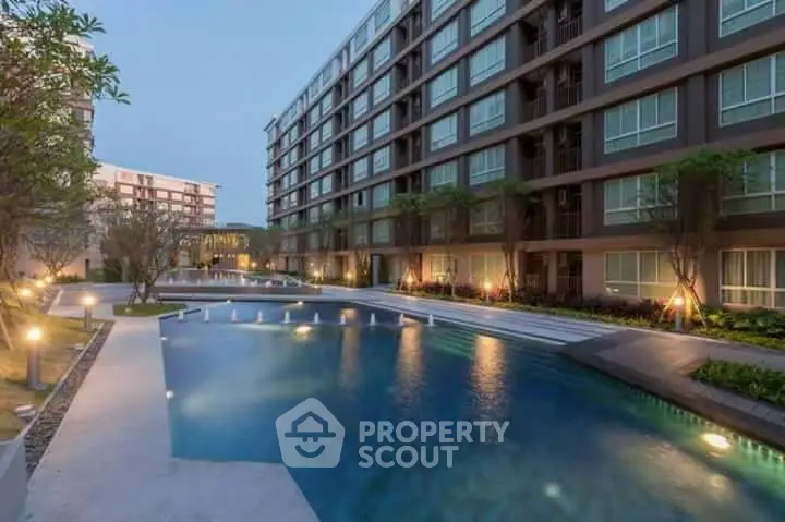 Modern apartment complex with illuminated pool and landscaped surroundings