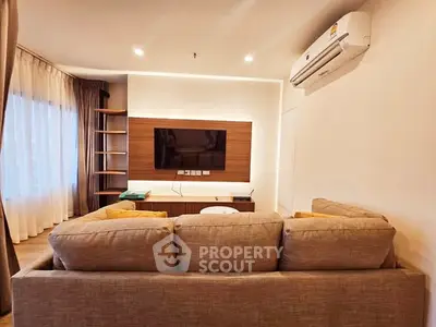 Modern living room with cozy sofa and wall-mounted TV, featuring elegant lighting and air conditioning.