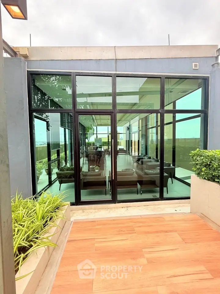 Luxurious modern building with expansive glass windows and lush greenery, offering a serene and stylish living space.