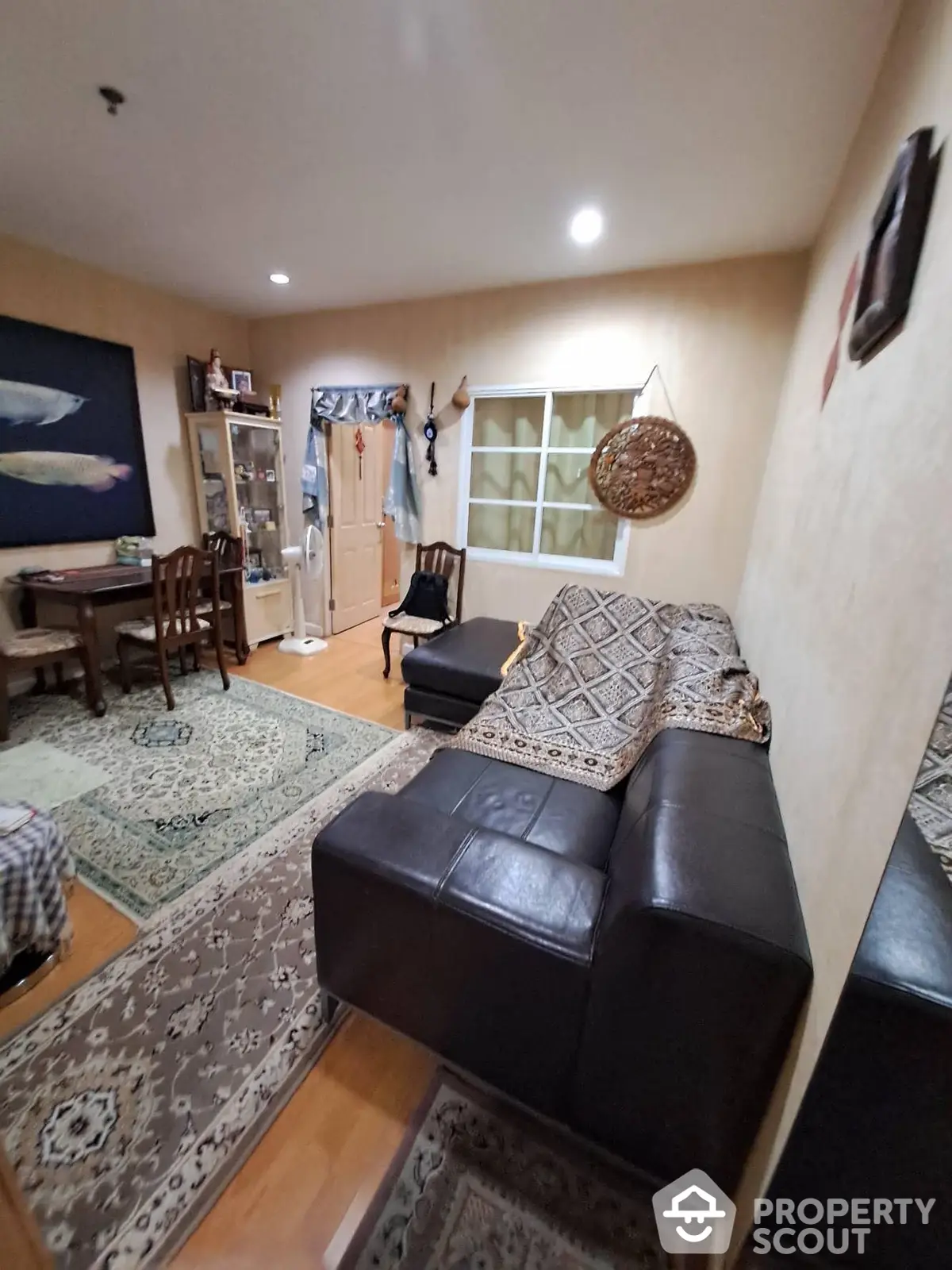 Spacious living room with elegant leather sofa, traditional area rugs, and tasteful wall art, perfect for comfortable family living and entertaining guests.