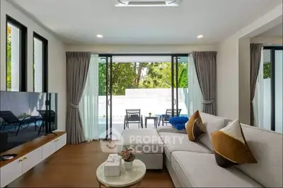 Spacious living room with modern decor and pool view, perfect for relaxation.