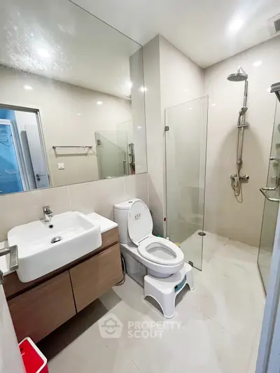 Modern bathroom with glass shower and sleek vanity in contemporary apartment.