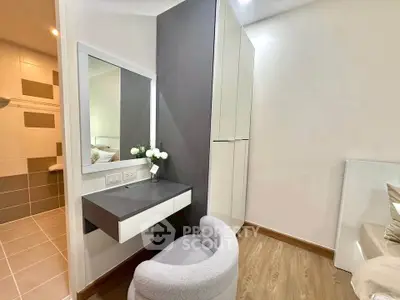 Modern bedroom with stylish vanity and cozy chair, featuring sleek design and neutral tones.