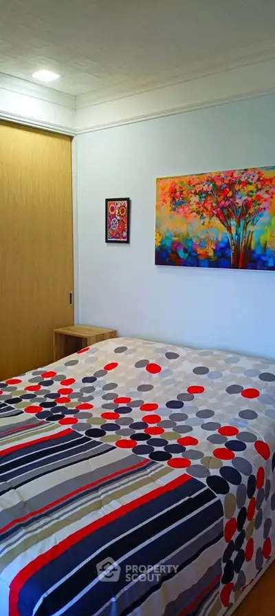 Cozy bedroom with colorful bedding and vibrant wall art, perfect for a relaxing retreat.