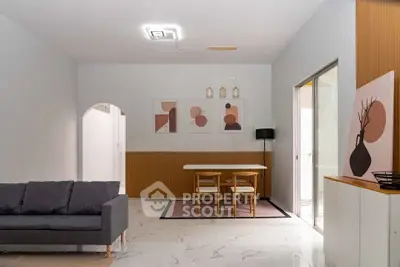 Modern living room with stylish decor and dining area, featuring contemporary art and elegant lighting.