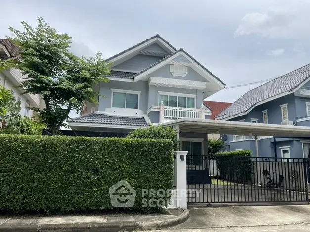 Charming two-story house with lush greenery and gated driveway in a serene neighborhood.