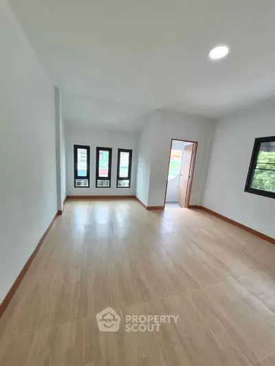 Spacious empty room with large windows and wooden flooring, perfect for customization.