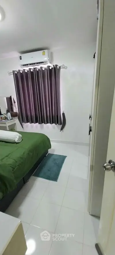 Cozy bedroom with green bedding and air conditioning, perfect for relaxation.