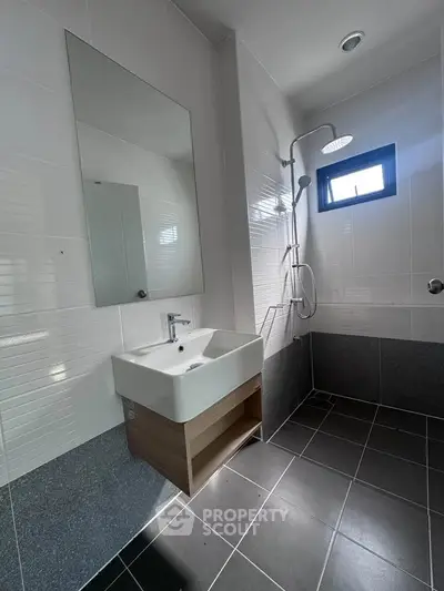 Modern bathroom with sleek design featuring a square sink and rainfall showerhead.