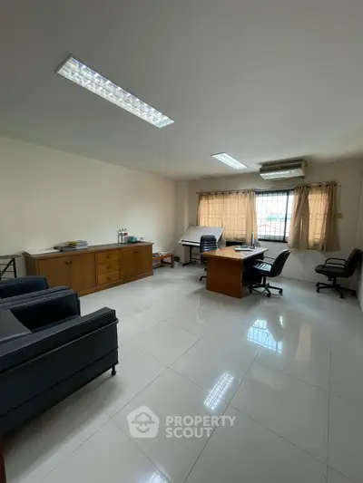 Spacious office room with modern furniture and large window for natural light.