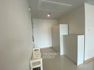 Minimalist storage area with white cabinets and bench in modern apartment.