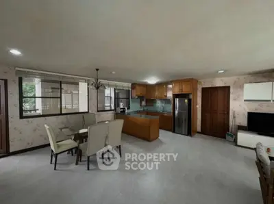 Spacious open-plan living room and kitchen with modern furnishings and large windows.