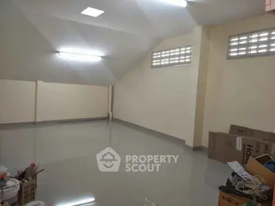 Spacious attic storage room with clean tiled flooring and ample lighting.