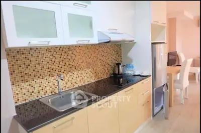 Modern kitchen with mosaic backsplash and sleek cabinetry in open layout apartment.