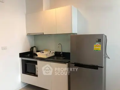 Modern kitchen with sleek cabinets and stainless steel fridge in a stylish apartment.