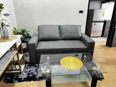 Modern living room with sleek gray sofa, glass coffee table, and stylish decor in a cozy apartment setting.