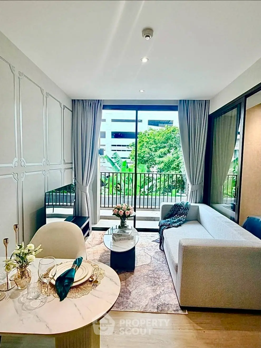 Modern living room with elegant decor and large window offering lush garden view.