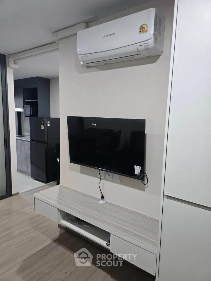 Modern living room with wall-mounted TV and air conditioning in stylish apartment.