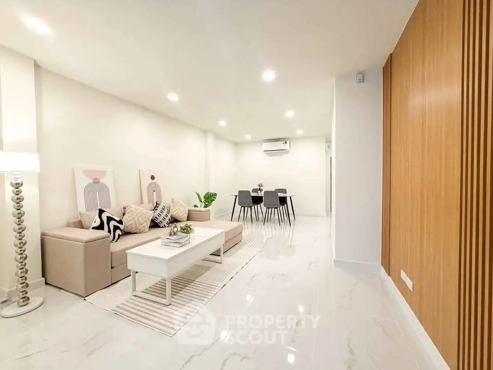 Spacious modern living room with elegant decor and dining area, featuring sleek furniture and ambient lighting.