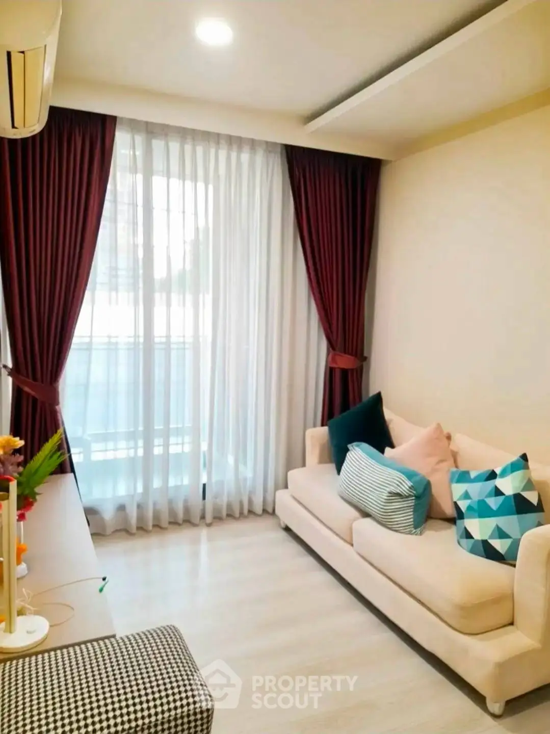 Cozy living room with modern decor and large window draped with elegant curtains.