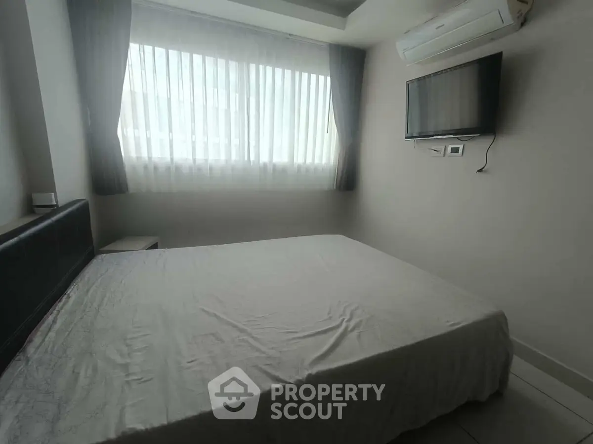 Cozy bedroom with natural light, air conditioning, and wall-mounted TV.