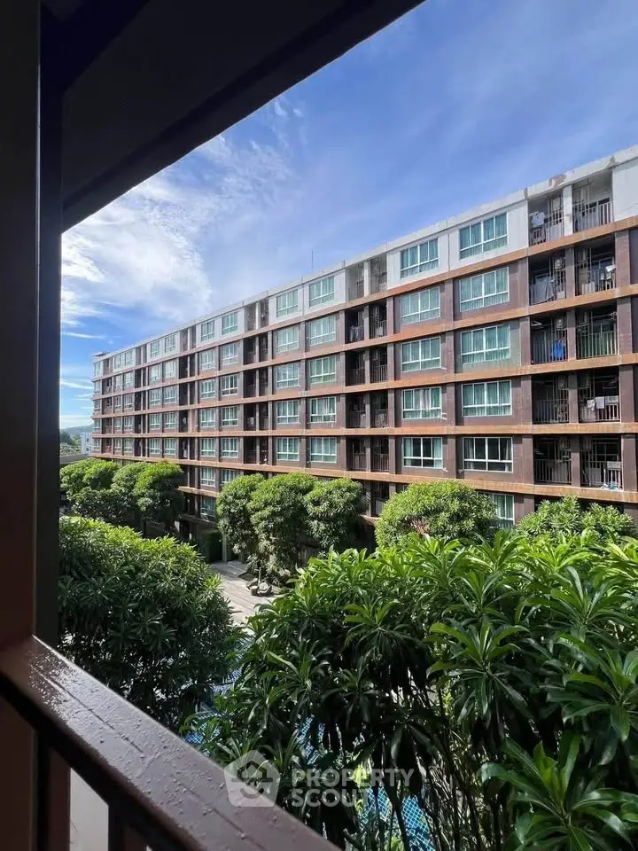Modern apartment building with lush greenery and clear blue sky view.