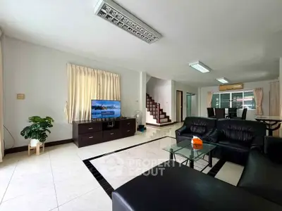 Spacious modern living room with sleek black leather sofas and elegant dining area, perfect for family gatherings.