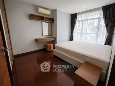 Spacious bedroom with hardwood floors and large window offering city views.