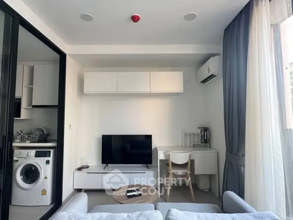 Modern living room with sleek furniture and integrated kitchen appliances in a stylish apartment.