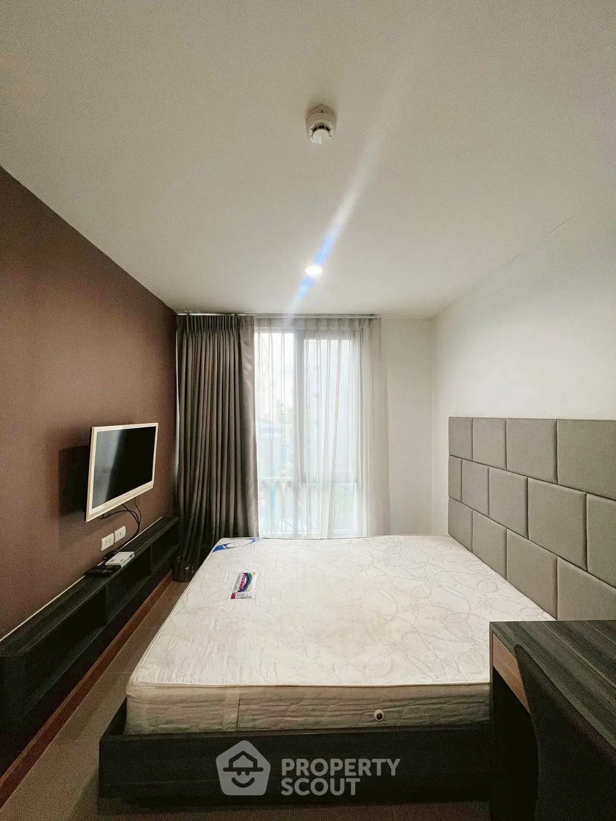 Modern bedroom with wall-mounted TV and large window for natural light.