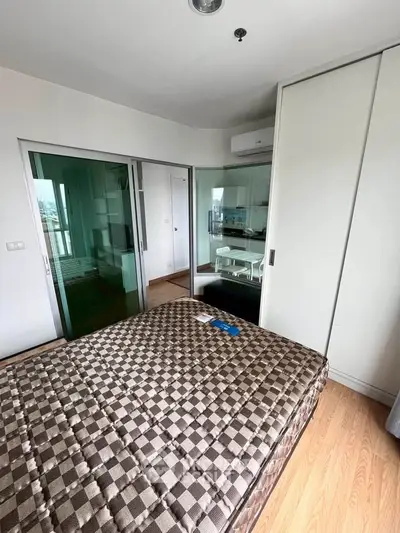 Modern bedroom with checkered bedspread and sliding glass doors leading to a kitchen area.