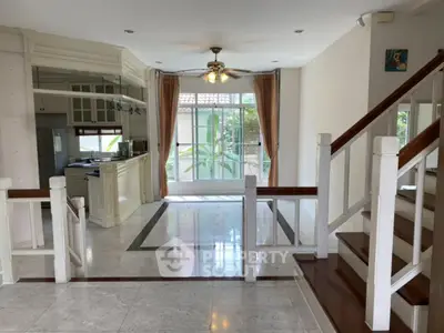 Spacious open-plan living area with elegant staircase and large windows in a modern home.