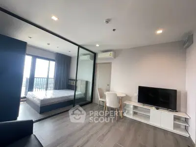 Modern open-plan living room with glass partitioned bedroom and balcony view.