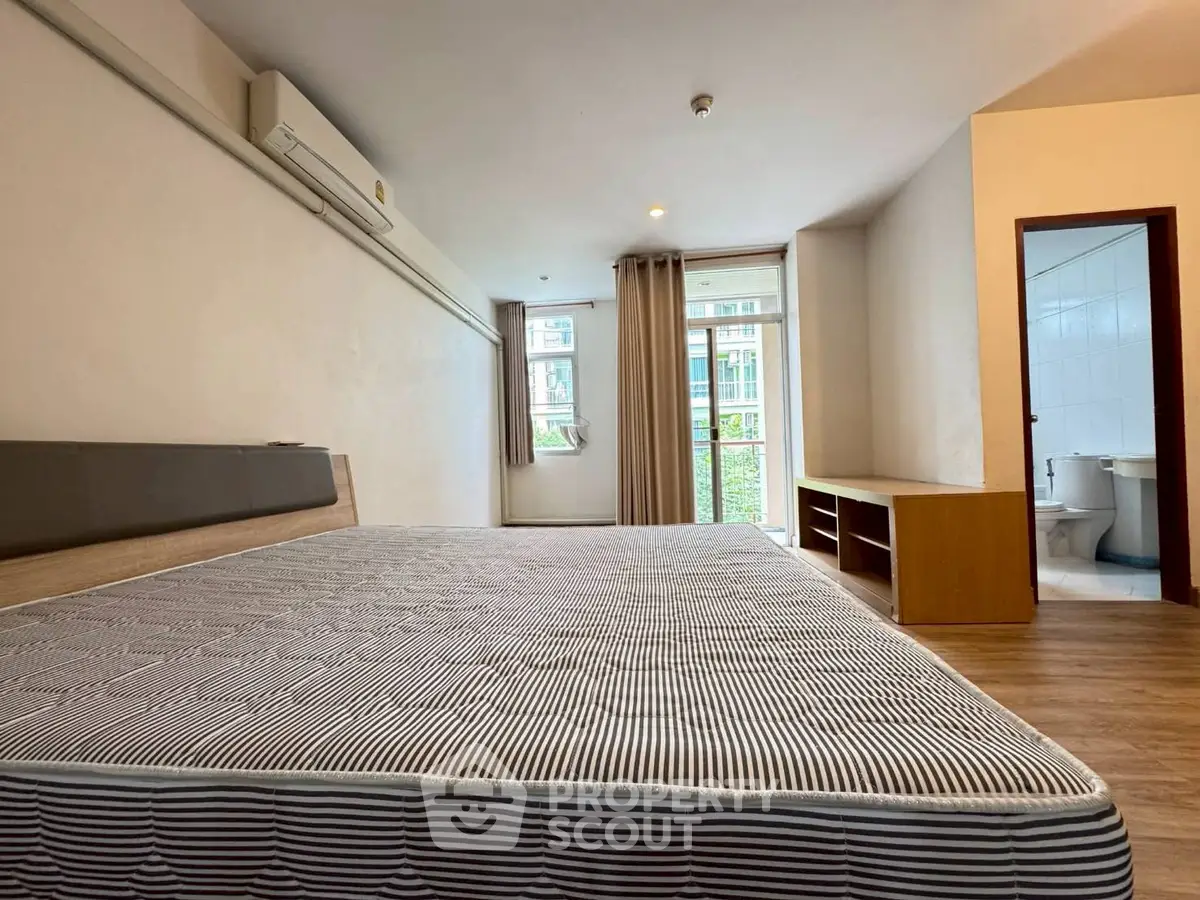 Spacious bedroom with large window and ensuite bathroom in modern apartment