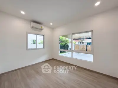 Spacious empty room with large windows and wooden flooring, perfect for customization.